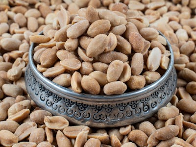Roasted Peanuts. Peanuts on wood floor. Bulk peanut kernels. Peanuts on a silver plate.