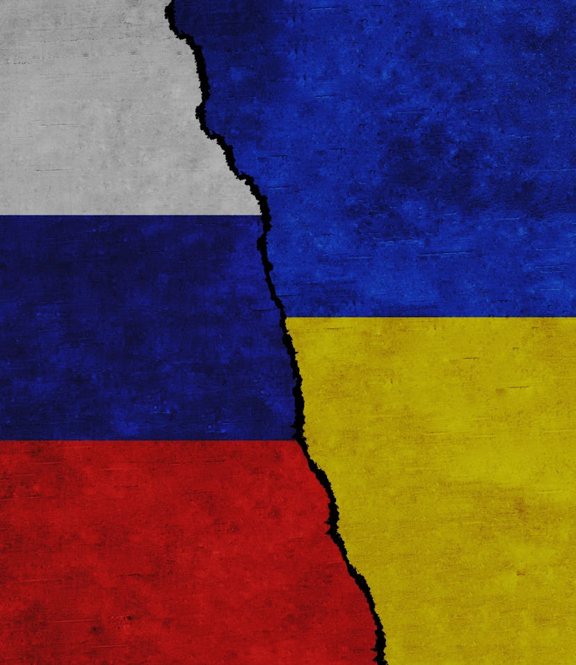 Russia and Ukraine painted flags on a wall with a crack. Russia and Ukraine relations. Ukraine and R...