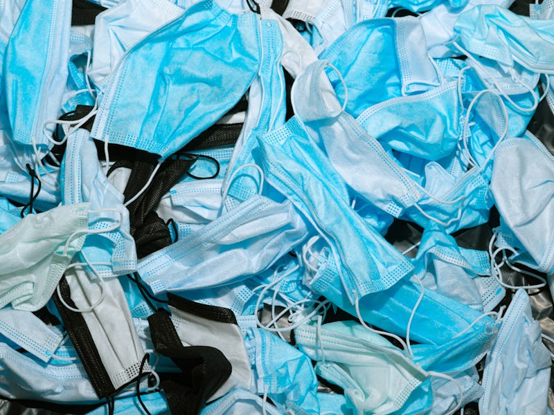 Medical masks on the table. Pile of used personal protective equipment PPE. Pollution by surgical ma...