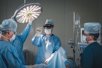 Group of surgeons using augmented reality holographic hololens glasses while operating in modern ope...
