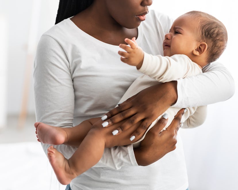 Portrait of black mother holding crying baby on hands