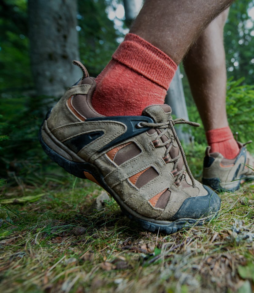 legs of the traveler in hiking boots with trekking poles