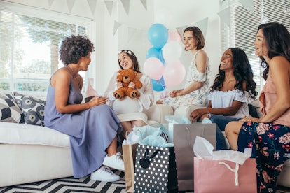 Pregnant woman celebrating baby shower party with friends. Pregnant woman receiving gifts from frien...