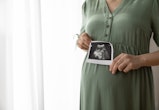 Cropped shot of pregnant woman showing sonogram image at camera, caption this photo with a pregnancy...