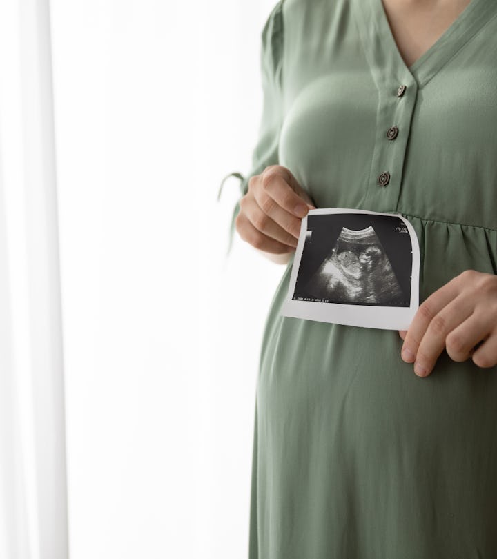 Cropped shot of pregnant woman showing sonogram image at camera, caption this photo with a pregnancy...