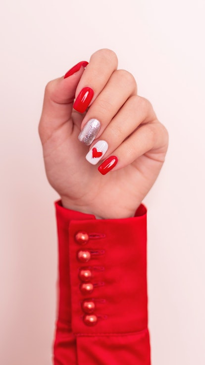 Hand with red manicure nails, heart, and Valentine's day design