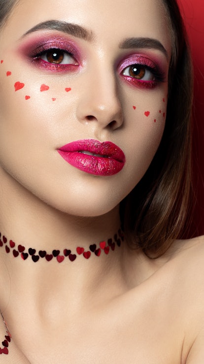 Portrait of young beautiful woman with fashion make up with little hearts on her cheek. Modern brigh...