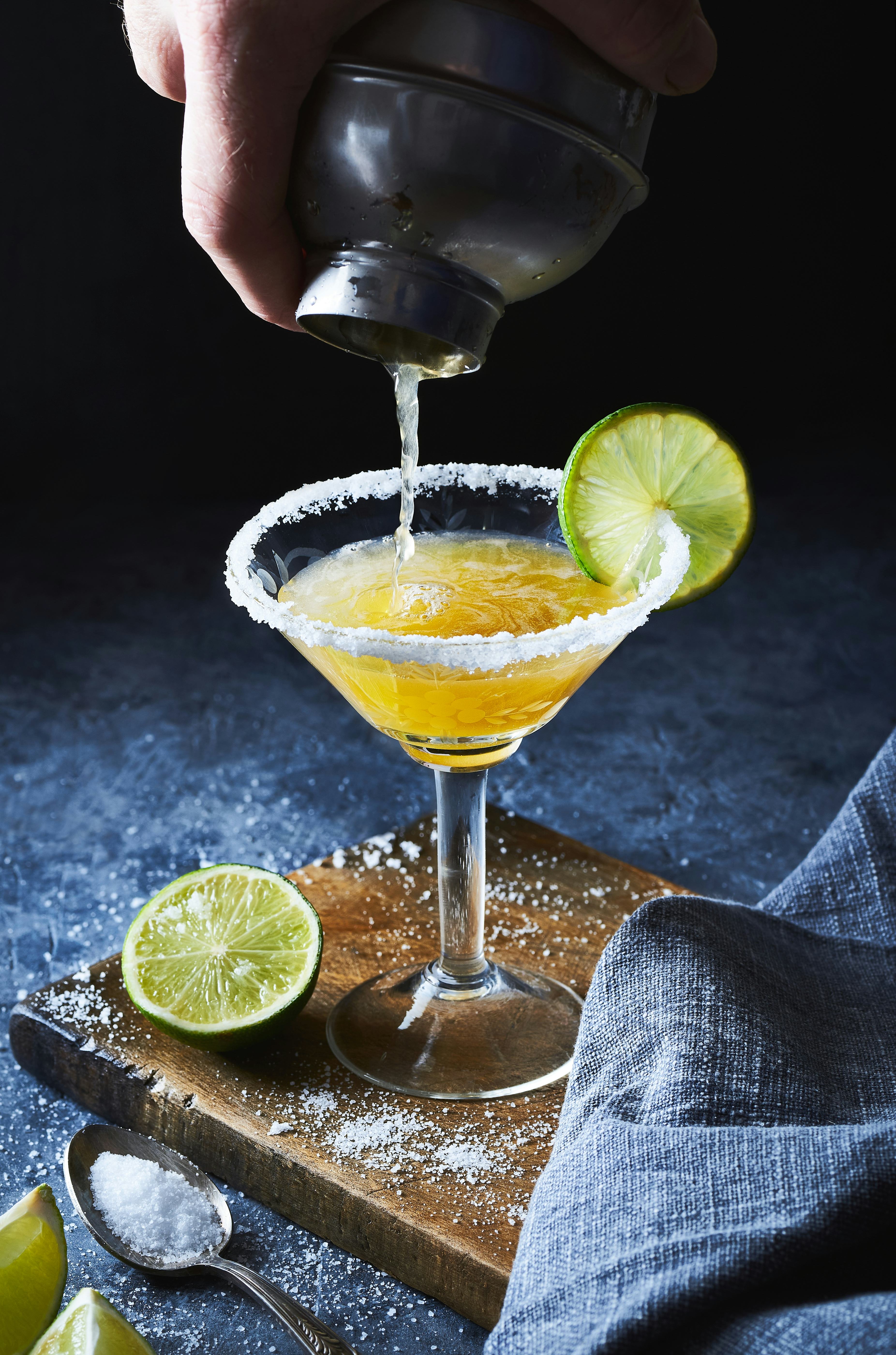 Bartender making margarita cocktail.Close up of classic lime margarita coctail with salt served in m...