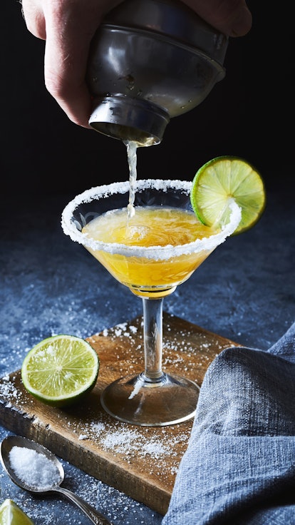 Bartender making margarita cocktail.Close up of classic lime margarita coctail with salt served in m...