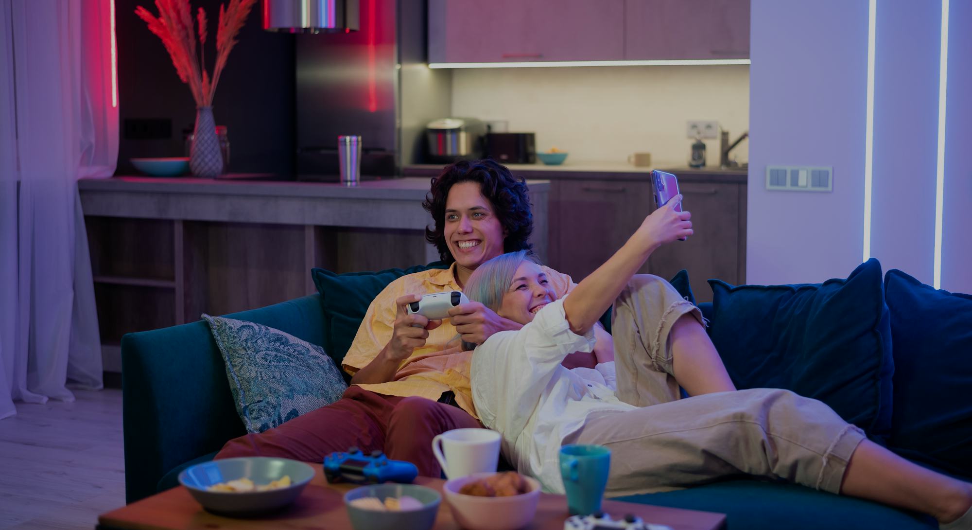 Guy playing video game while girl using smartphone for social media. Spending time together at home.