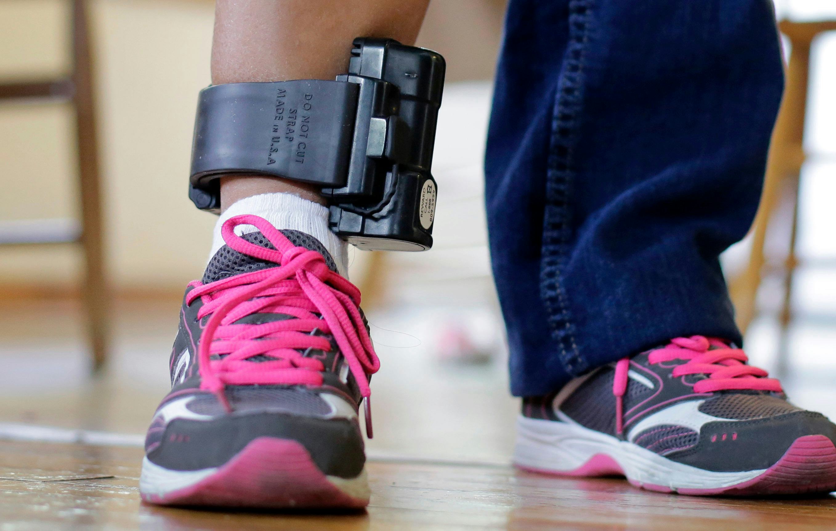 An immigrant from El Salvador that entered the country illegally wears an ankle monitor at a shelter...