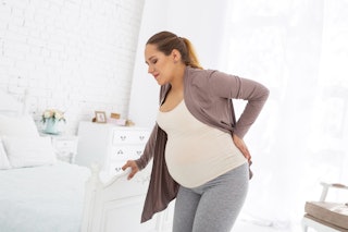 Discomfort during pregnancy. Angry pregnant woman staying and touching her back