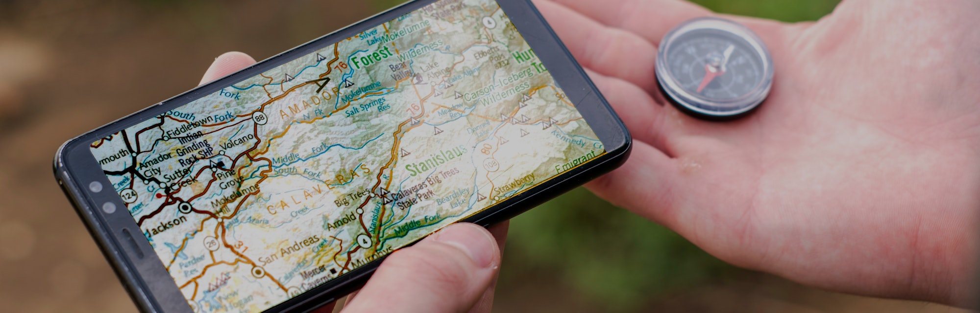 a tourist navigates the terrain holding a compass and a smartphone with a map concept tourism travel...