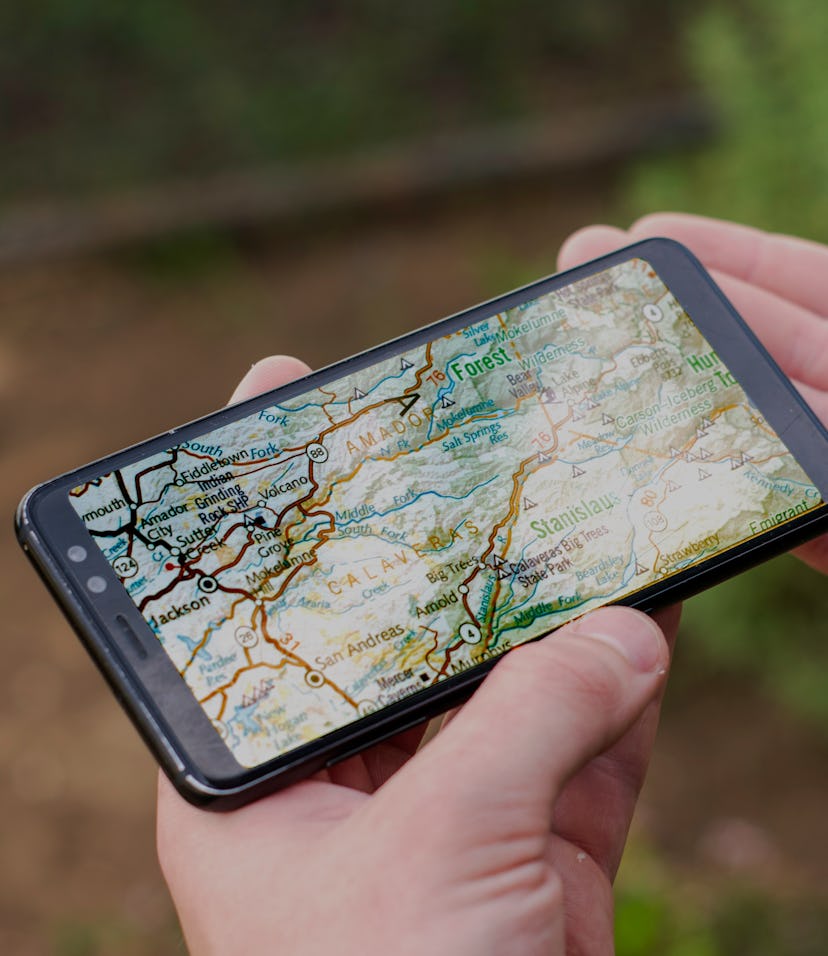 a tourist navigates the terrain holding a compass and a smartphone with a map concept tourism travel...