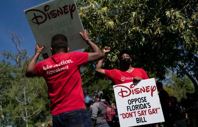 Two LGBTQ supporters hold signs to protest Disney's stance on LGBTQ issues in Glendale, Calif., . Wi...