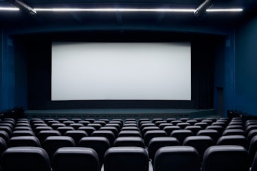 Empty cinema hall with screen and black row chairs. Concept of empty modern movie theatre.