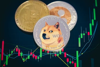 Focus select and blur Dogecoin cryptocurrency silver symbol and stock chart candlestick on tablets. ...