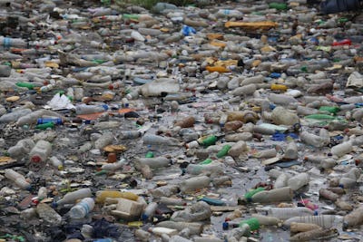 Pollution by plastic bottles in the water. Pattern of dirty floating objects in the sea. Symbol of a...