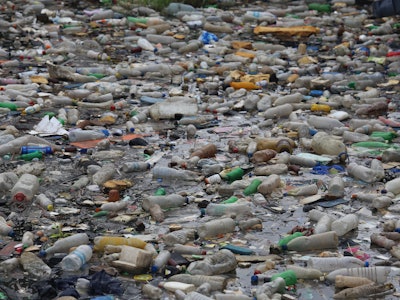 Pollution by plastic bottles in the water. Pattern of dirty floating objects in the sea. Symbol of a...