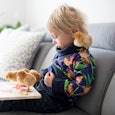 Little toddler child, blond boy, reading book with sweet chicks around him