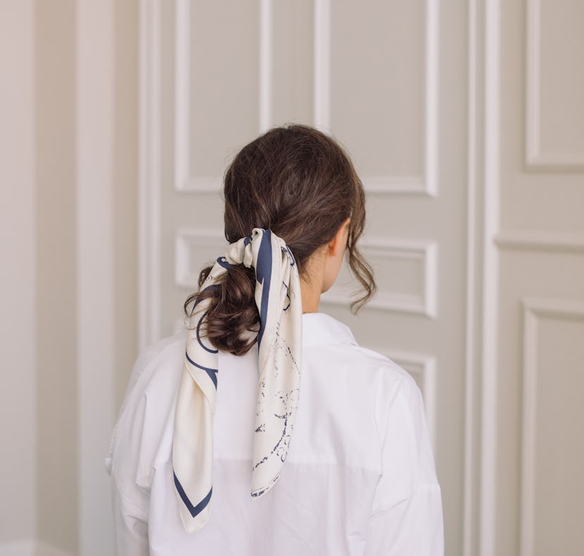 Young woman wearing silk scarf in hair, using products to keep it from frizzing.