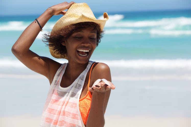 Fun portrait of an african american woman with shell in hand at the beach