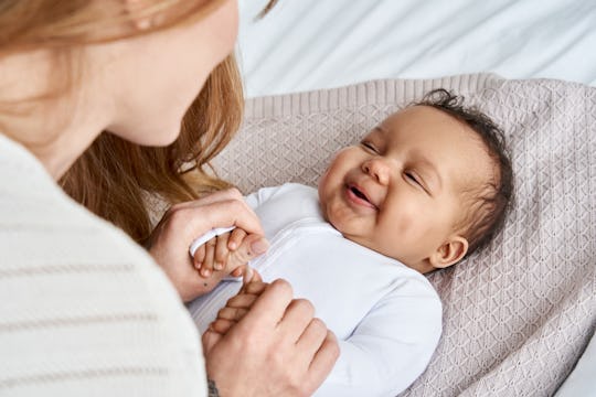 Mother holding the hands of a little baby boy who she'll choose one of these Roman boy names for