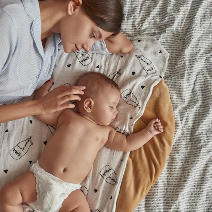 Portrait of lovely undressed angel like baby, peacefully sleeping near mother after breastfeeding in...