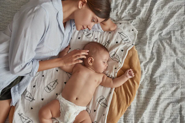 Portrait of lovely undressed angel like baby, peacefully sleeping near mother after breastfeeding in...