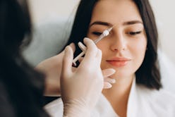 Portrait of young Caucasian woman getting botox cosmetic injection in forehead. Beautiful woman gets...