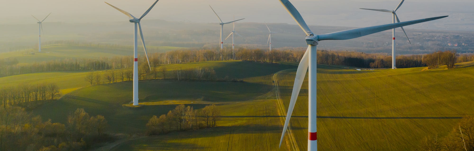 Panoramic view of wind farm or wind park, with high wind turbines for generation electricity with co...