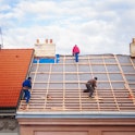 three builders replace the tiled roof in the old town