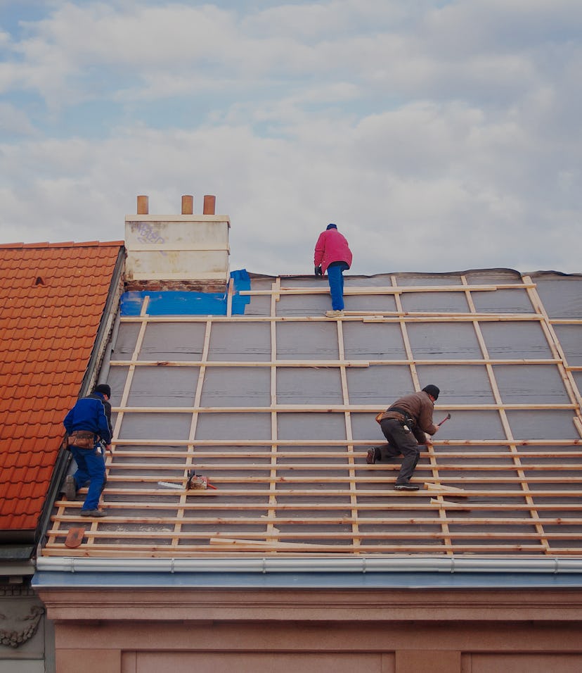 three builders replace the tiled roof in the old town