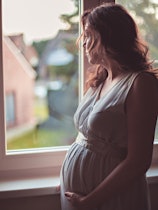 Pregnant woman looks thoughtfully out the window
