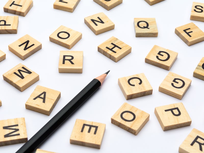 Black pencil and scattered alphabet letters on wooden blocks on white background