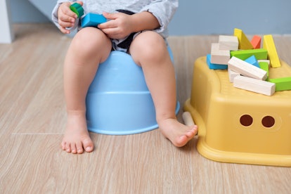 baby sitting on a potty playing with blocks