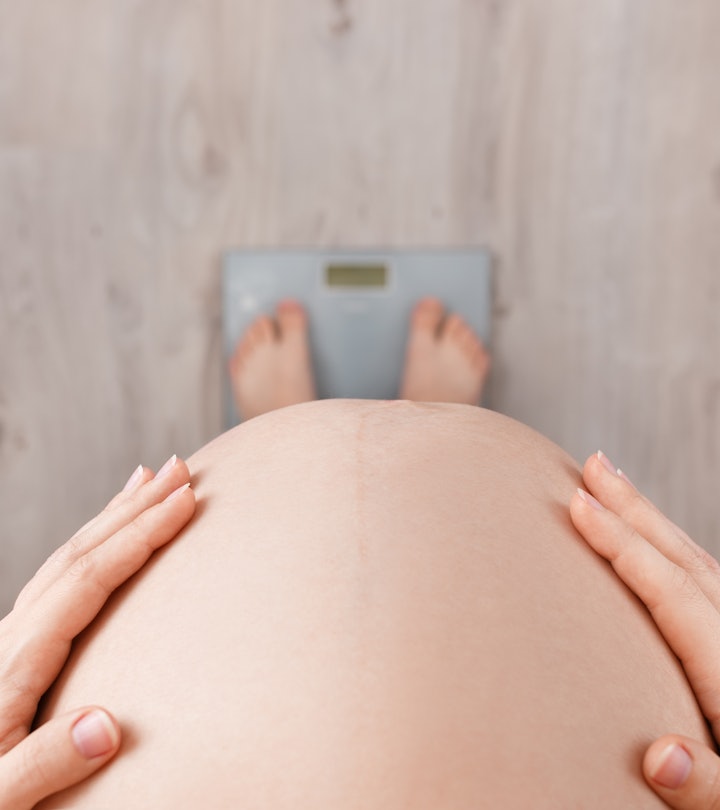 close up, overhead view of a pregnant woman's belly while she's standing on a scale, not gaining wei...