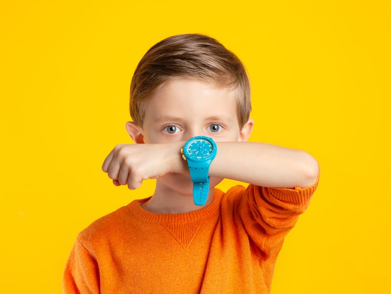 A child with a wristwatch. A beautiful 6-year-old boy shows the time on his watch. Portrait of a hap...