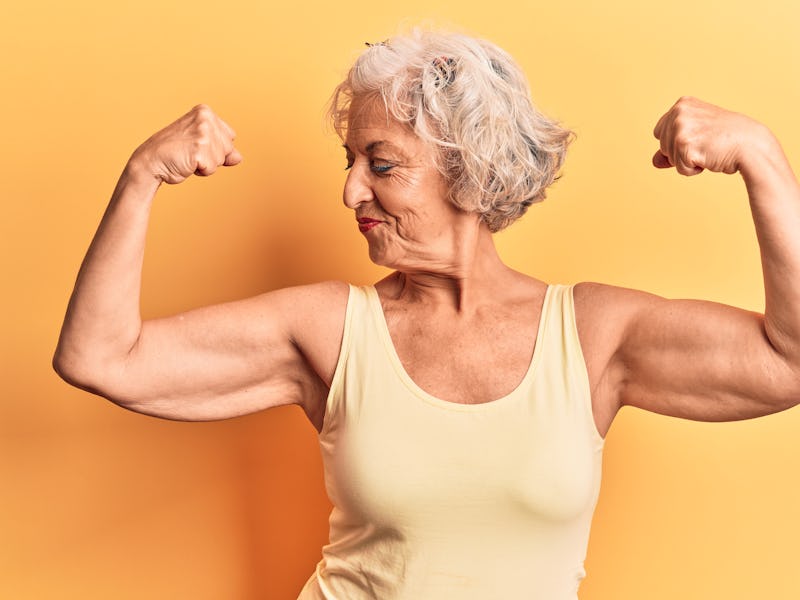 Senior grey-haired woman wearing casual clothes showing arms muscles smiling proud. fitness concept....