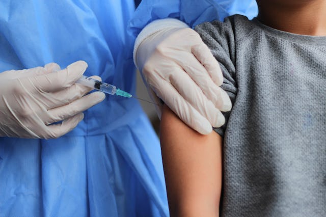 Little boy getting vaccinated from Covid-19. A young doctot's hand holding a vaccine syringe.