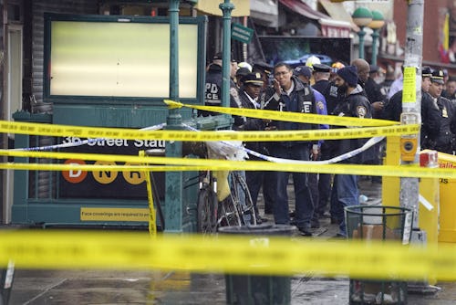 New York City Police Department personnel gather at the entrance to a subway stop in the Brooklyn bo...