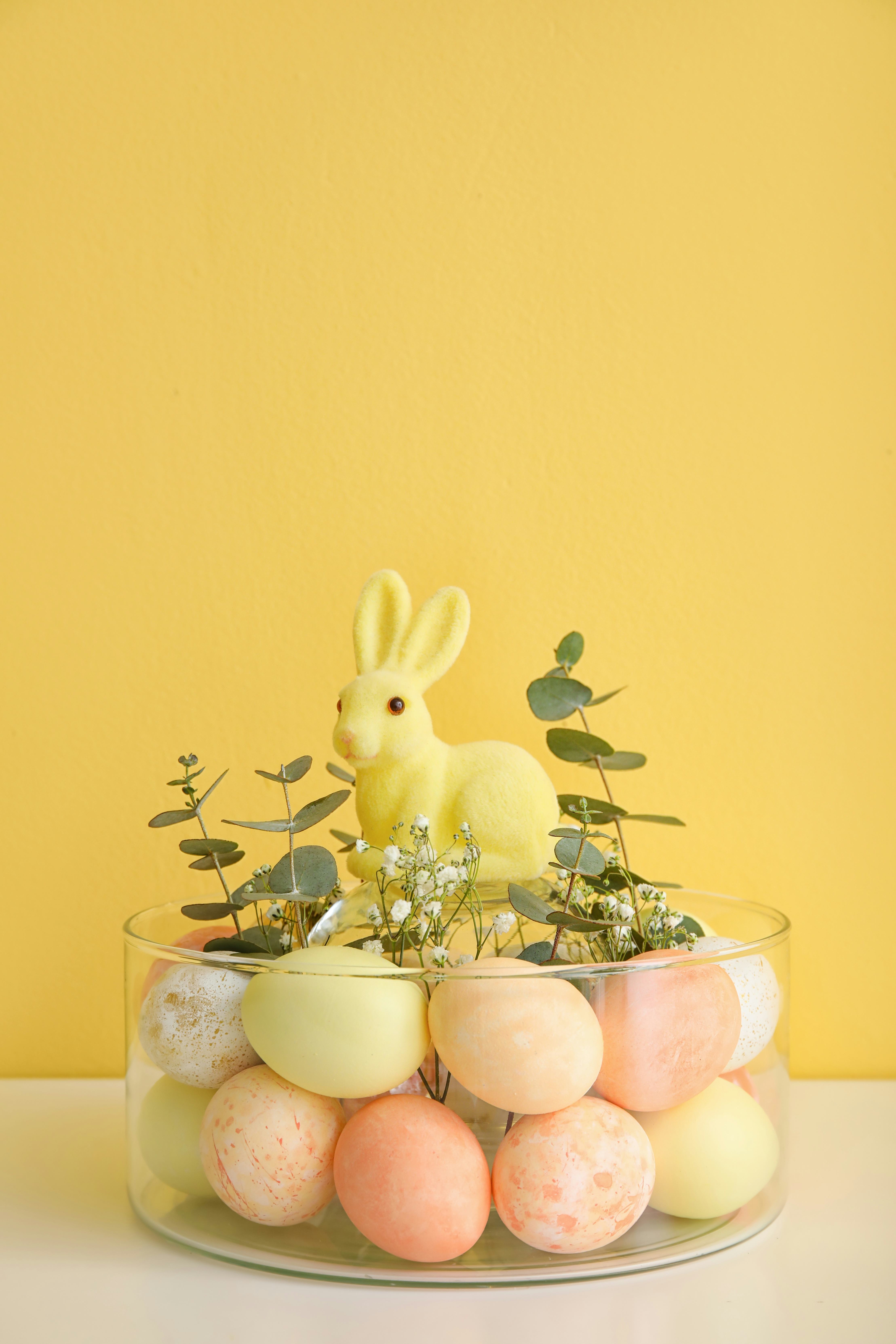 Bowl with Easter eggs, rabbit, and floral decor as Easter table setting.