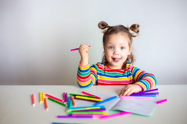 Little girl, a 3 year old girl, with a ponytail hairstyle in a multi-colored colorful striped jacket...