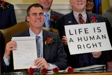 Oklahoma Gov. Kevin Stitt poses for a photo with the bill he signed, making it a felony to perform a...