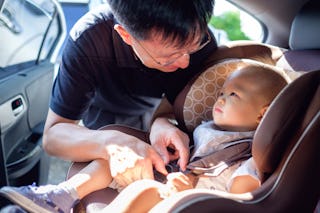 Smiling father unbuckles baby before removing car seat to trade in at Target's semiannual event.