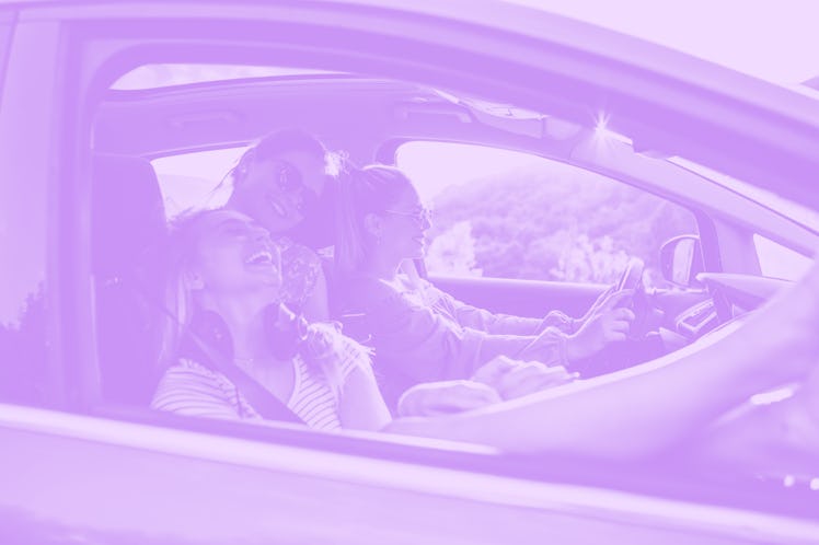 Three female friends driving in a car on a post-graduation trip 