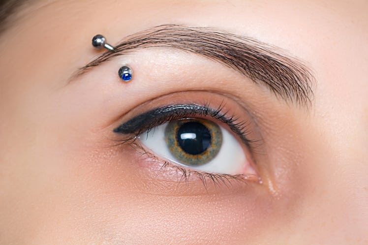 Up close photo of an eyebrow piercing with a barbell.