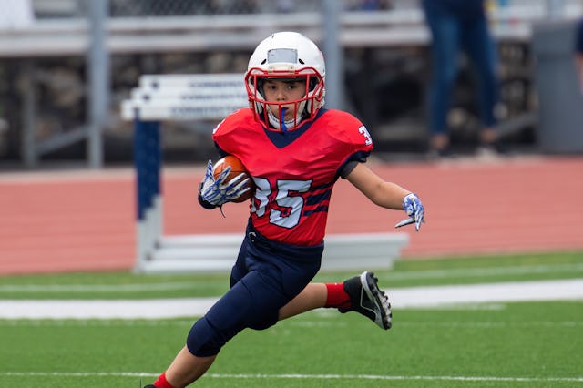 A young boy playing tackle football, a sport half of Americans disapprove of children playing, likel...