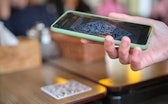 Closeup of guest hand ordering meal in restaurant while scanning qr code with mobile phone for onlin...
