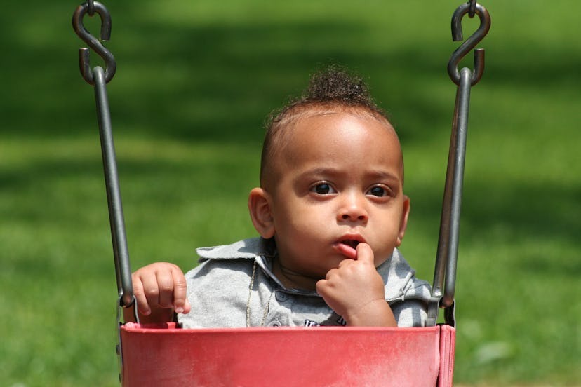 African American infant in a red swing to represent baby names that mean sun.
